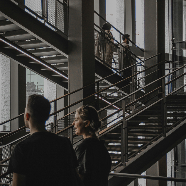 People moving through a layered industrial stairwell